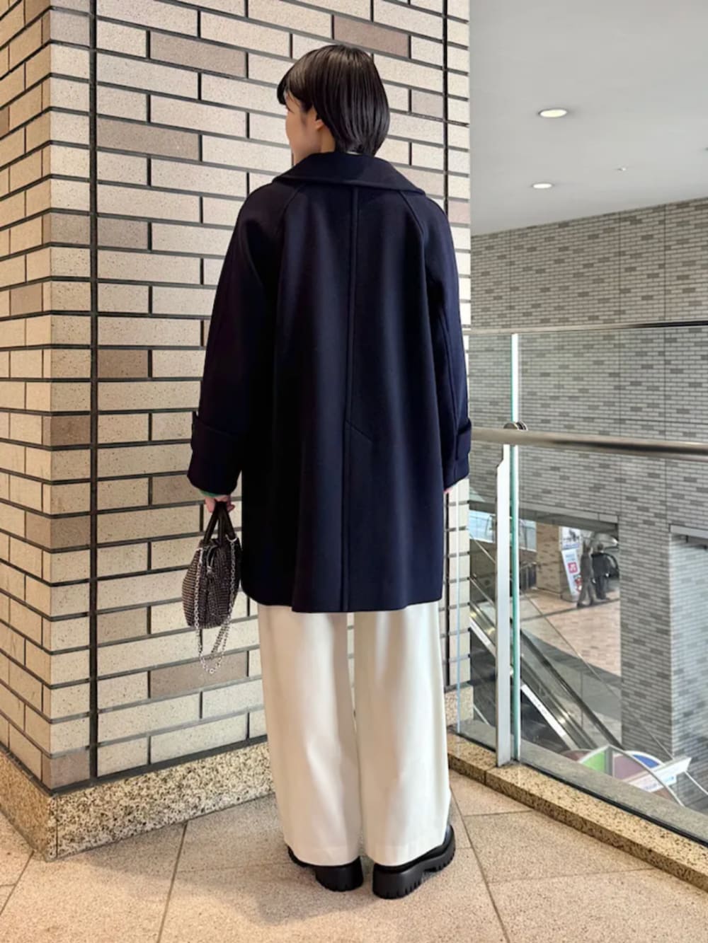 ブラック系のブーツ、ブラック系のショルダーバッグ、ブルー系のステンカラーコートを着用したレディースの冬コーディネートの2枚目の写真