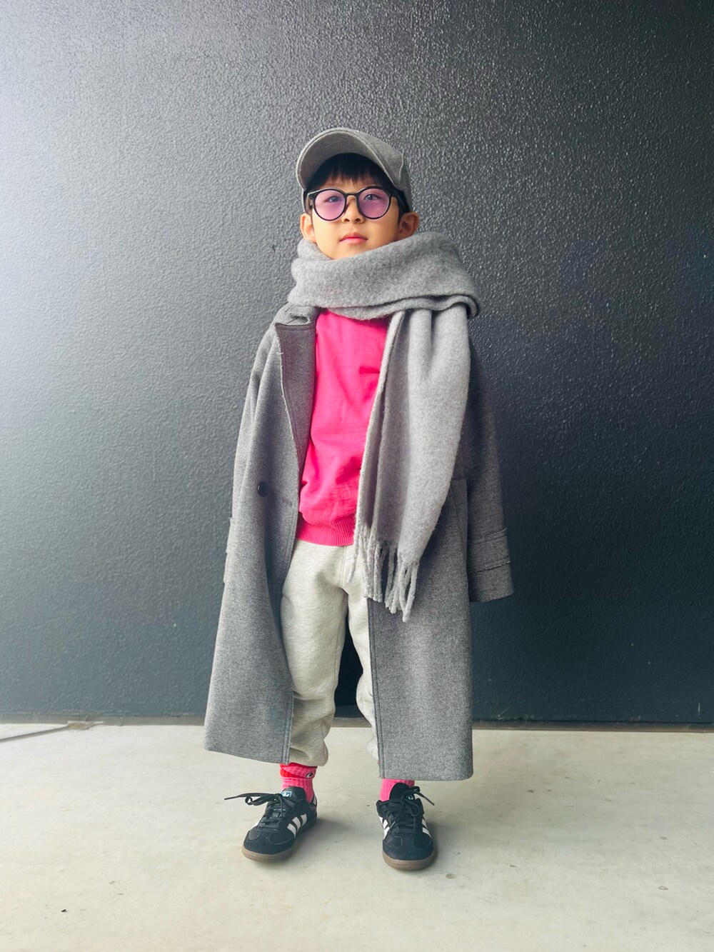 ピンク系のニット/セーター、グレー系のチェスターコート、グレー系のスウェットパンツを着用したキッズの冬コーディネートの2枚目の写真