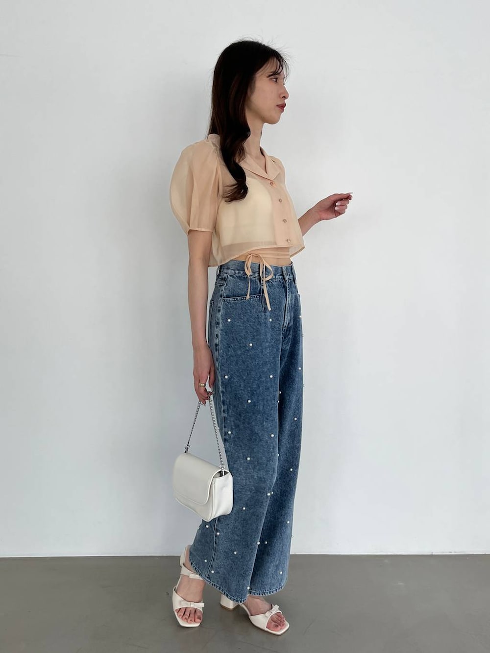 ホワイト系のショルダーバッグ、ブルー系のデニムパンツ、ホワイト系のキャミソールを着用したレディースの春コーディネートの4枚目の写真