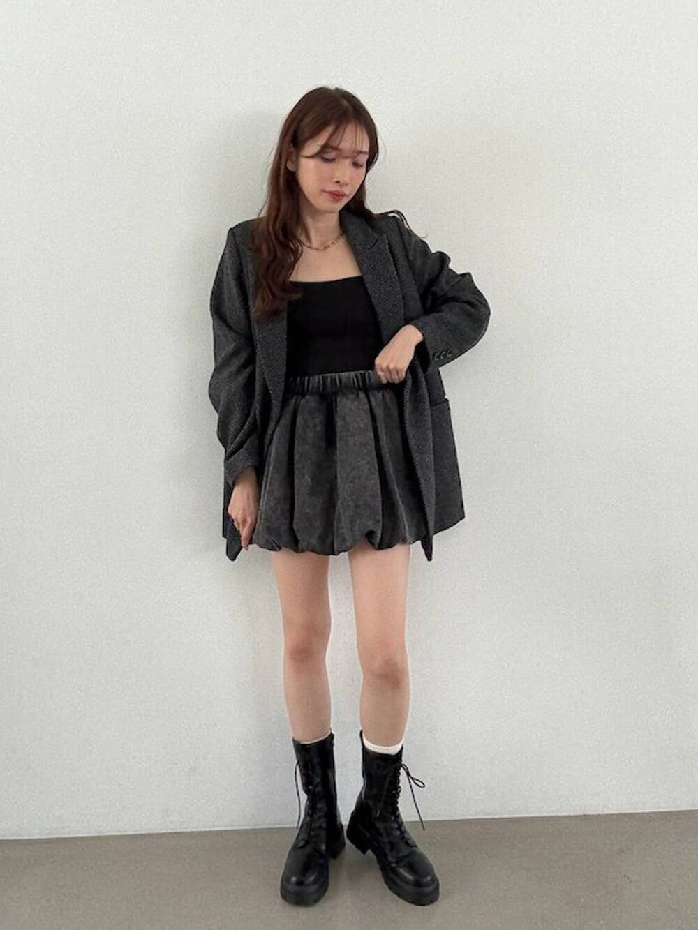 グレー系のテーラードジャケット、ブラック系のキャミソール、ブラック系のブーツを着用したレディースの秋コーディネートの5枚目の写真