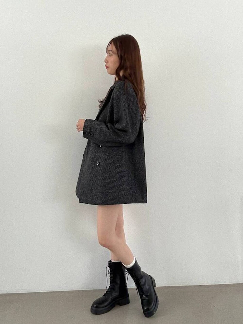 グレー系のテーラードジャケット、ブラック系のキャミソール、ブラック系のブーツを着用したレディースの秋コーディネートの3枚目の写真