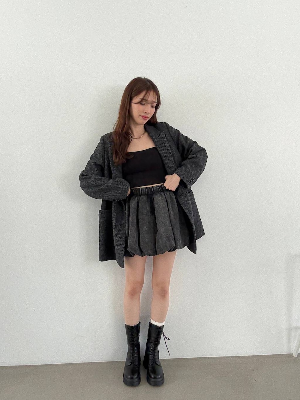 グレー系のテーラードジャケット、ブラック系のキャミソール、ブラック系のブーツを着用したレディースの秋コーディネートの5枚目の写真