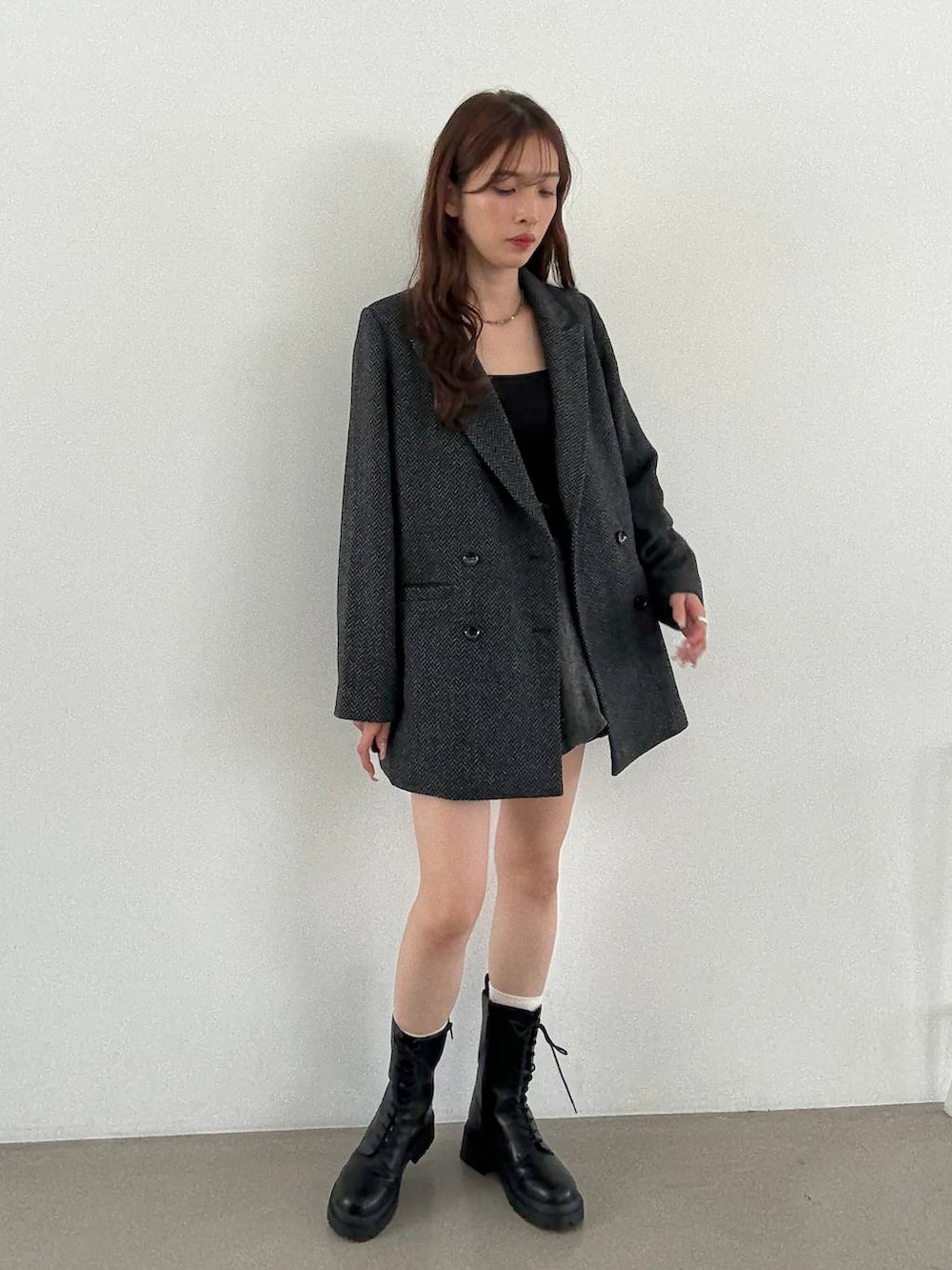 グレー系のテーラードジャケット、ブラック系のキャミソール、ブラック系のブーツを着用したレディースの秋コーディネートの2枚目の写真