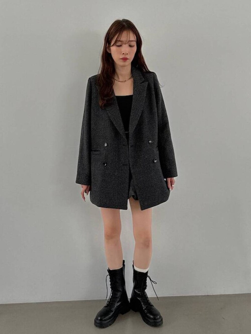 グレー系のテーラードジャケット、ブラック系のキャミソール、ブラック系のブーツを着用したレディースの秋コーディネートの4枚目の写真