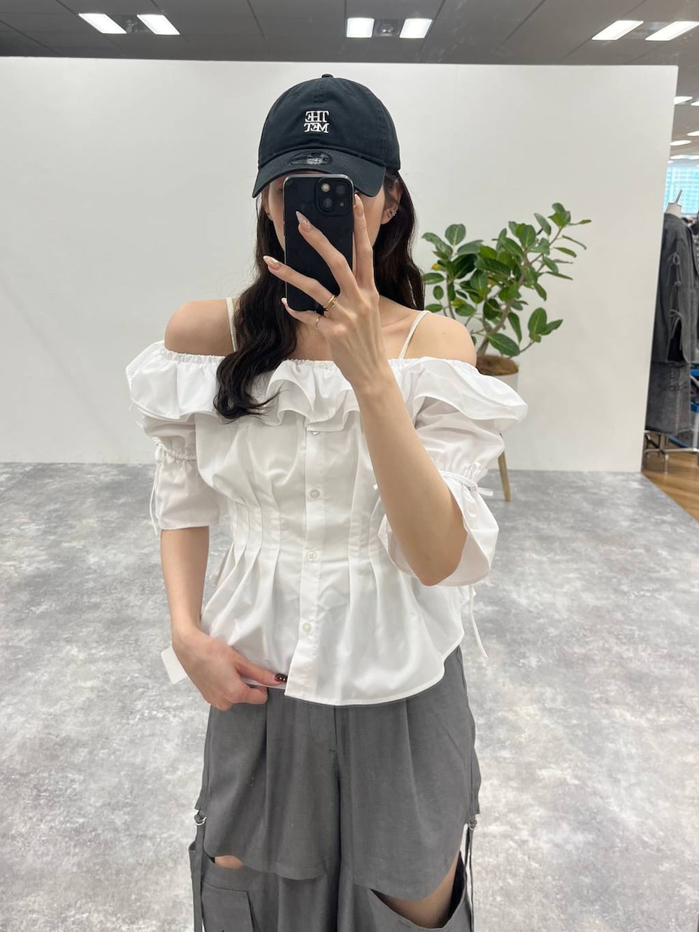 グレー系のカーゴパンツ、ホワイト系のシャツ/ブラウス、ブラック系のキャップを着用したレディースの春コーディネートの2枚目の写真