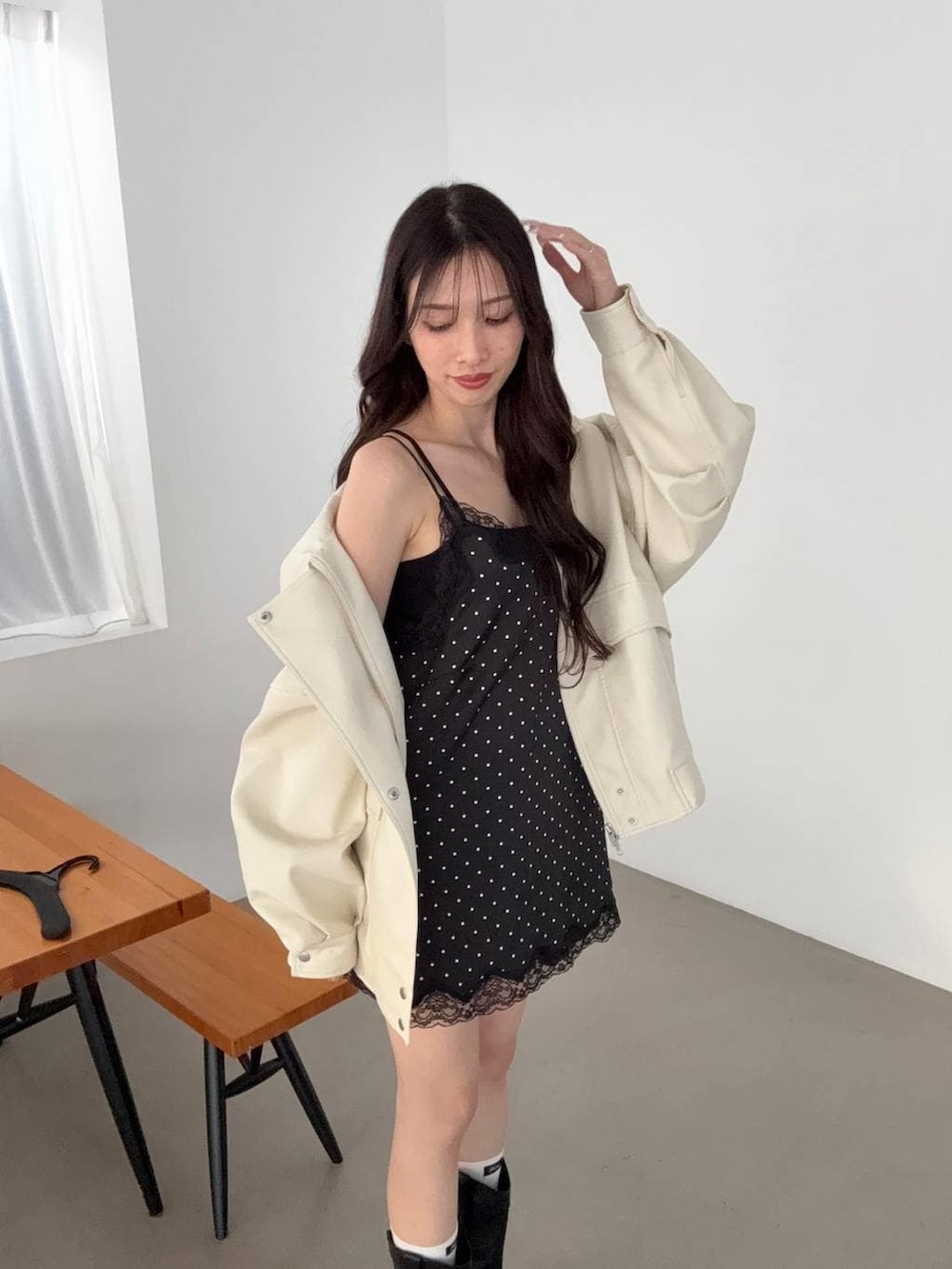 ブラック系のキャミソール、ブラック系のブーツ、ホワイト系のブルゾンを着用したレディースの冬コーディネートの3枚目の写真