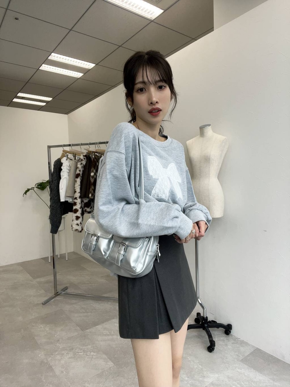 グレー系のスウェット、シルバー系のショルダーバッグ、グレー系のスカートを着用したレディースの秋コーディネートの3枚目の写真
