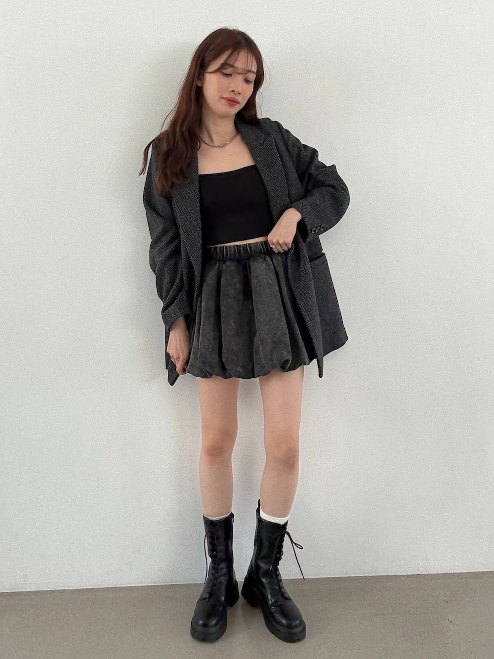 グレー系のテーラードジャケット、ブラック系のキャミソール、ブラック系のブーツを着用したレディースの秋コーディネートの3枚目の写真