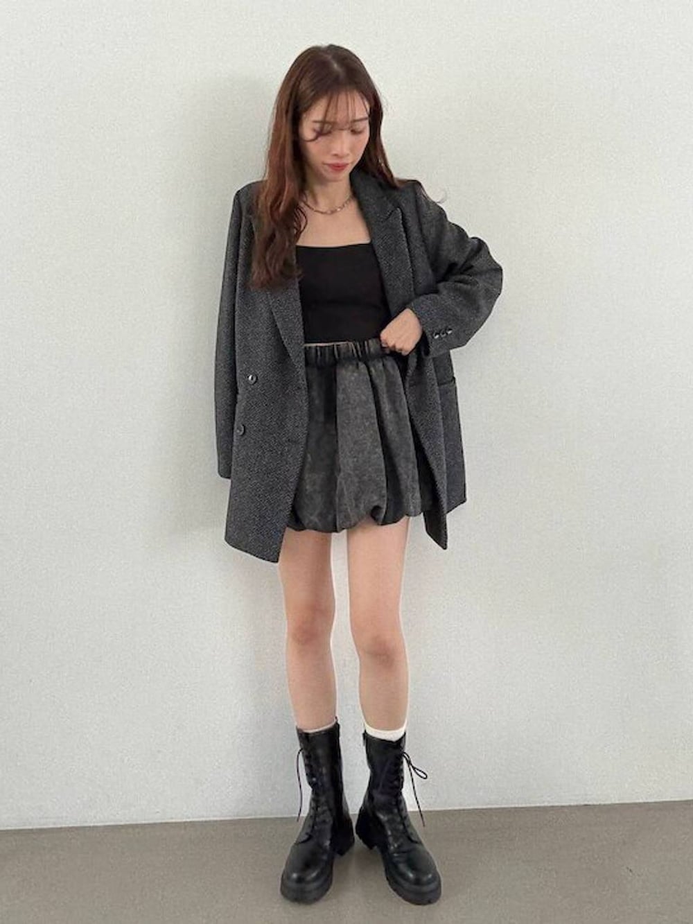 グレー系のテーラードジャケット、ブラック系のキャミソール、ブラック系のブーツを着用したレディースの秋コーディネートの2枚目の写真