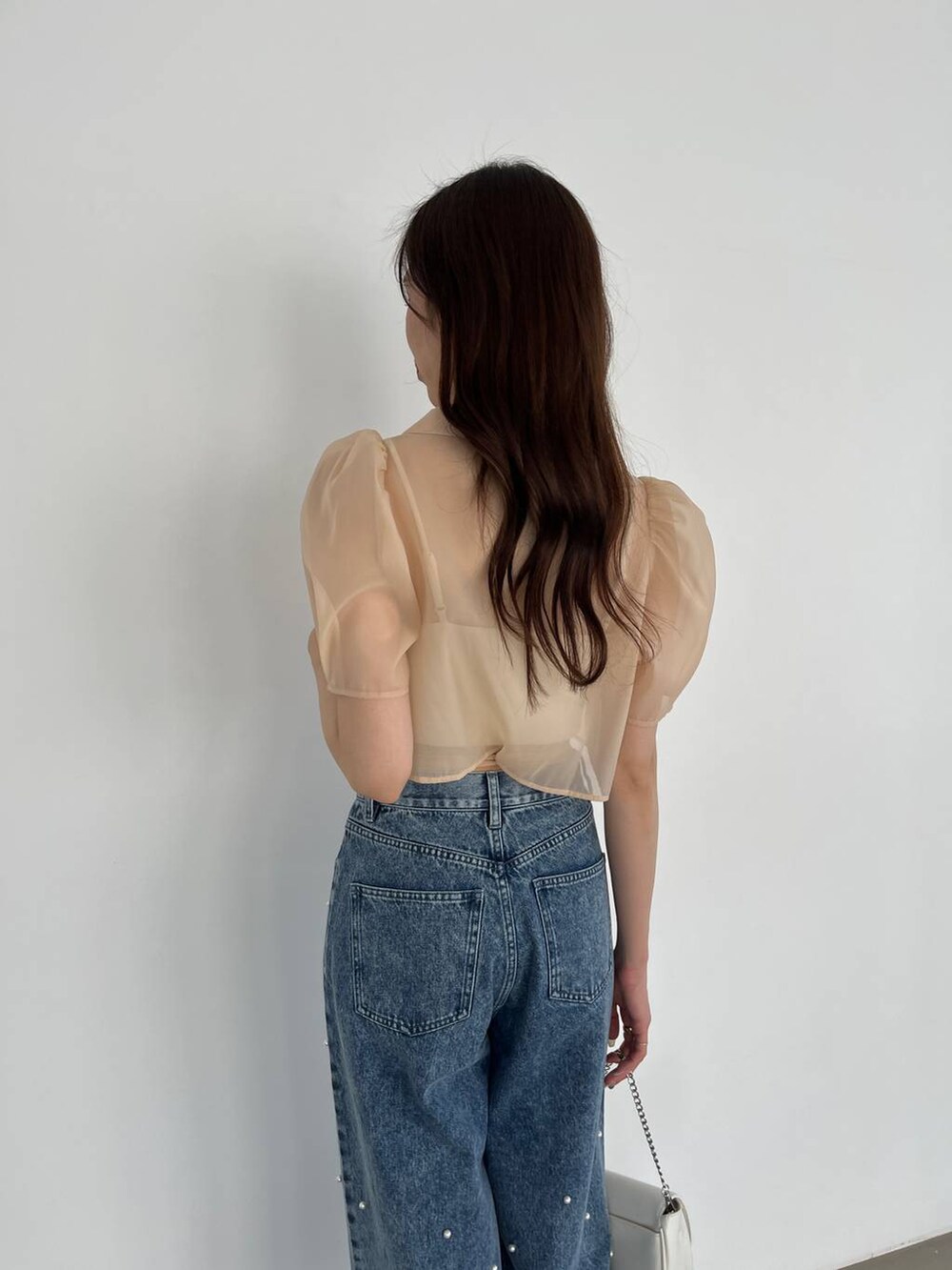 ホワイト系のショルダーバッグ、ブルー系のデニムパンツ、ホワイト系のキャミソールを着用したレディースの春コーディネートの5枚目の写真