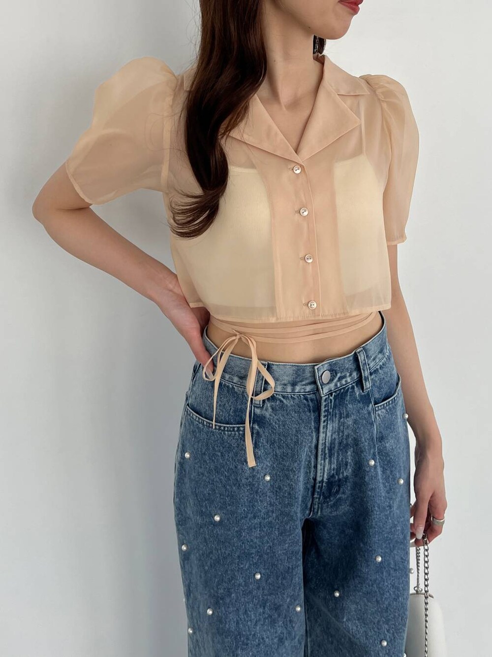 ホワイト系のショルダーバッグ、ブルー系のデニムパンツ、ホワイト系のキャミソールを着用したレディースの春コーディネートの2枚目の写真