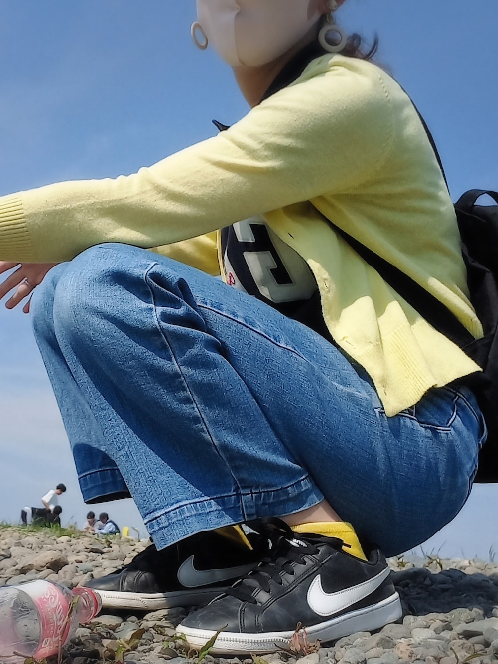 ブラック系のバックパック/リュック、ブラック系のスニーカー、ブルー系のデニムパンツを着用したレディースの春コーディネートの2枚目の写真