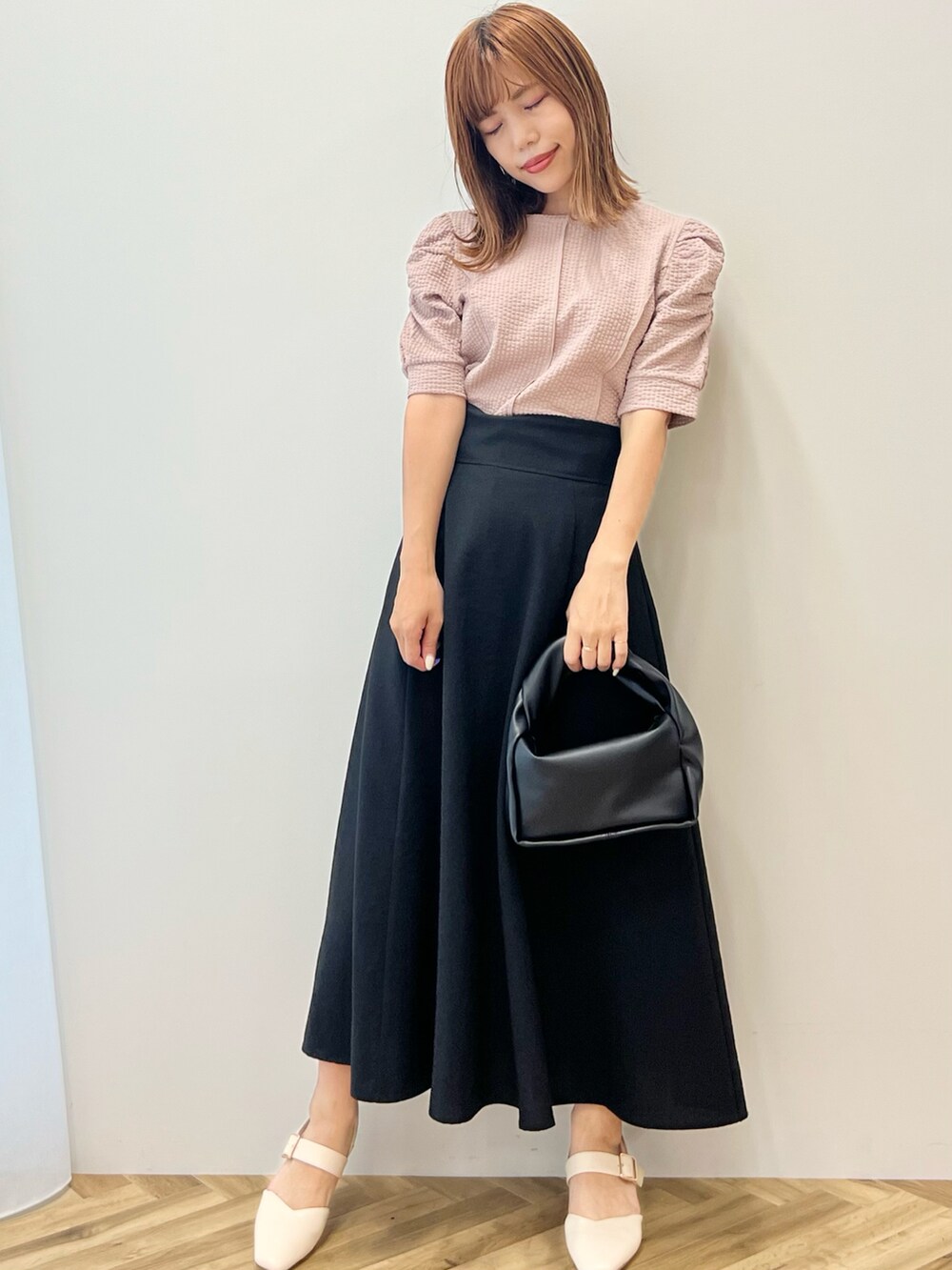 ホワイト系のパンプス、ブラック系のスカート、ベージュ系のTシャツ/カットソーを着用したレディースの夏コーディネートの2枚目の写真