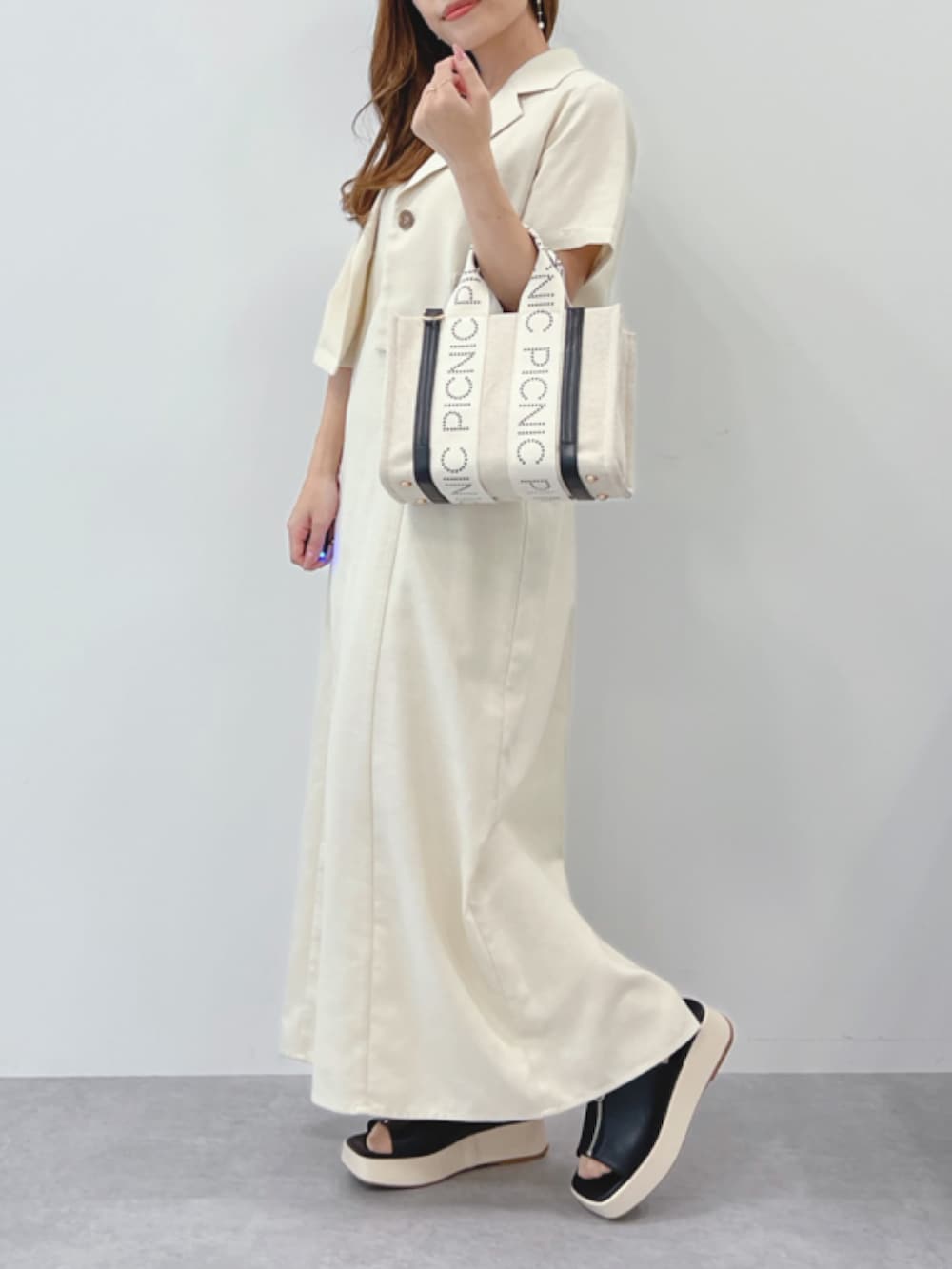 ベージュ系のワンピース、ベージュ系のシャツ/ブラウス、ブラック系のサンダルを着用したレディースの春コーディネートの2枚目の写真