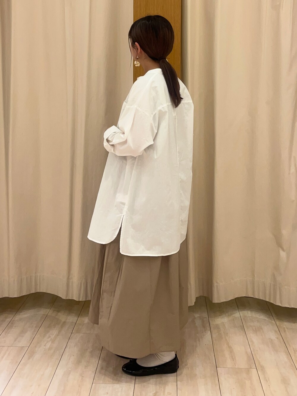 ブラック系のワンピース、ホワイト系のトップス、ベージュ系のタンクトップを着用したレディースの春コーディネートの3枚目の写真