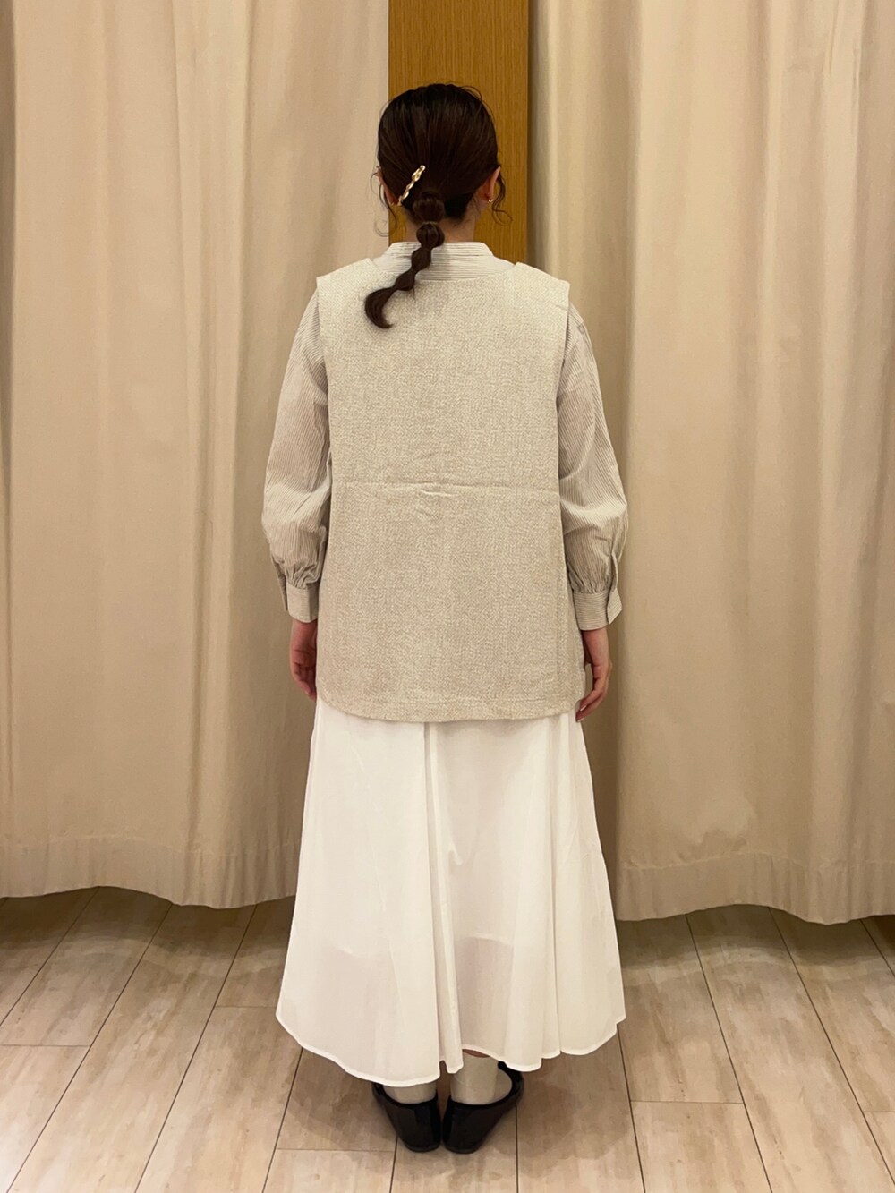 ホワイト系のスカート、ベージュ系のベストを着用したレディースの春コーディネートの4枚目の写真