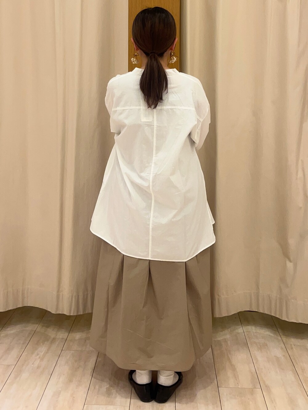 ブラック系のワンピース、ホワイト系のトップス、ベージュ系のタンクトップを着用したレディースの春コーディネートの2枚目の写真