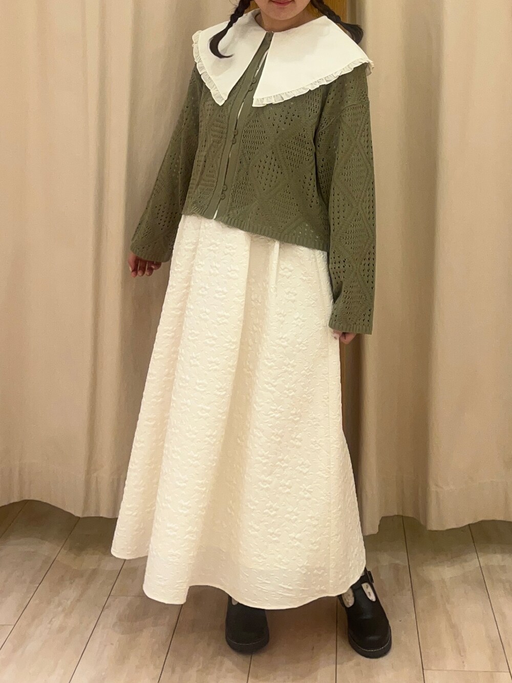 ブラック系のその他シューズ、ホワイト系のスカート、グリーン系のカーディガン/ボレロを着用したレディースの春コーディネートの2枚目の写真