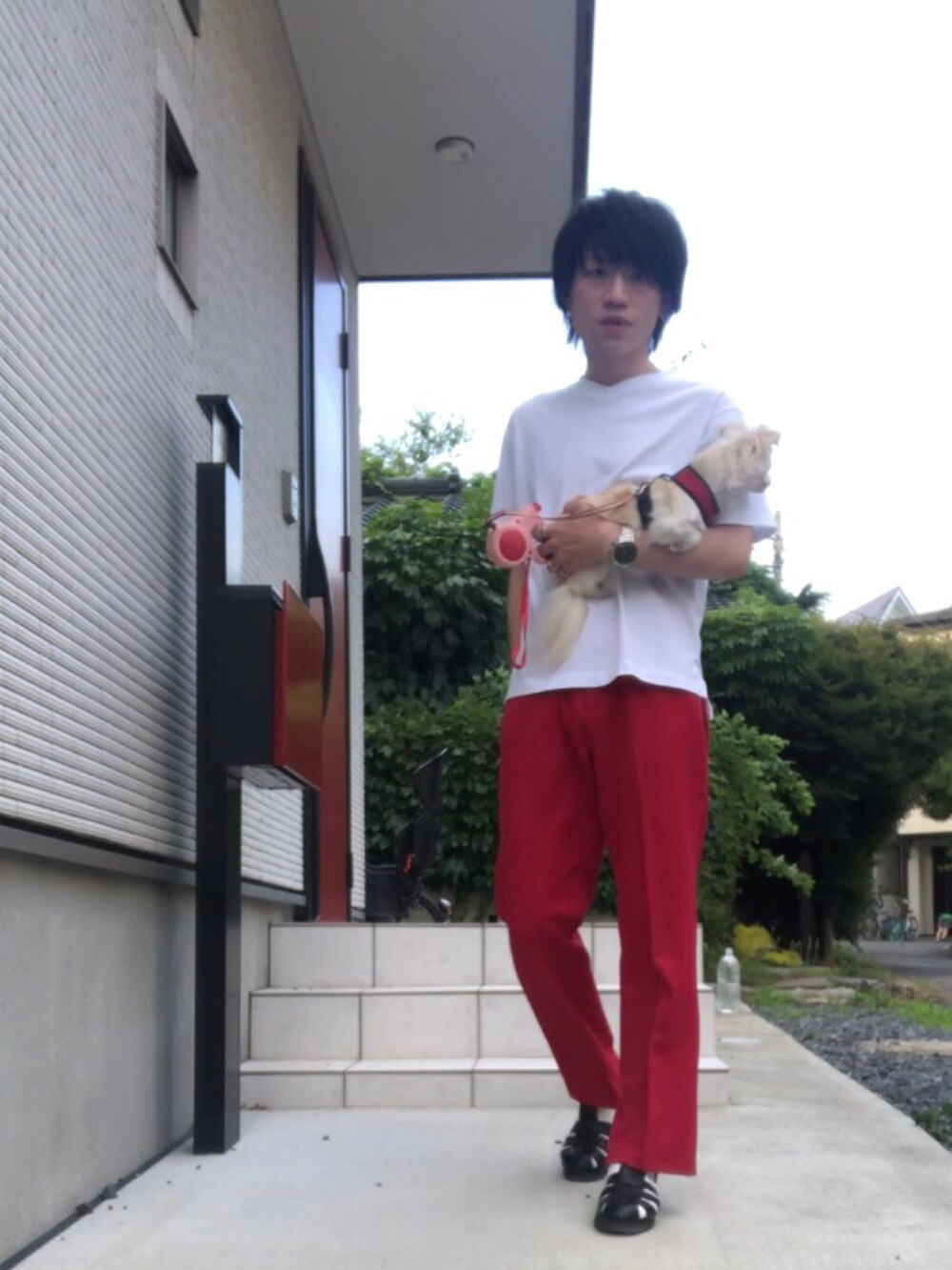 ホワイト系のTシャツ/カットソー、レッド系のスラックス、ブラック系のサンダルを着用したメンズの夏コーディネートの2枚目の写真