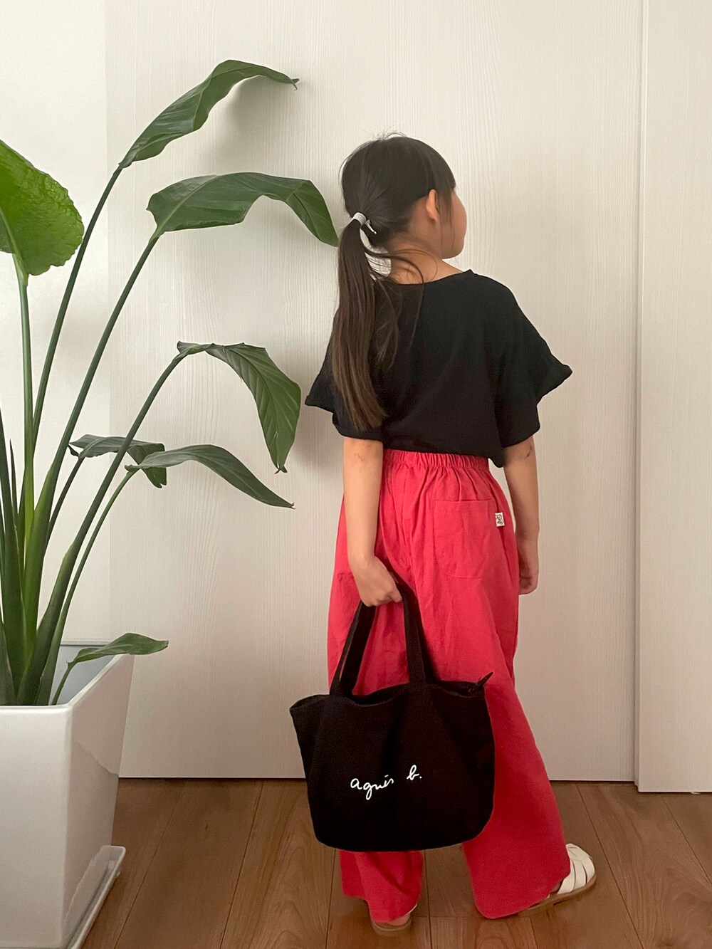 ブラック系のTシャツ/カットソー、ブラック系のハンドバッグ、ホワイト系のサンダルを着用したキッズの春コーディネートの3枚目の写真