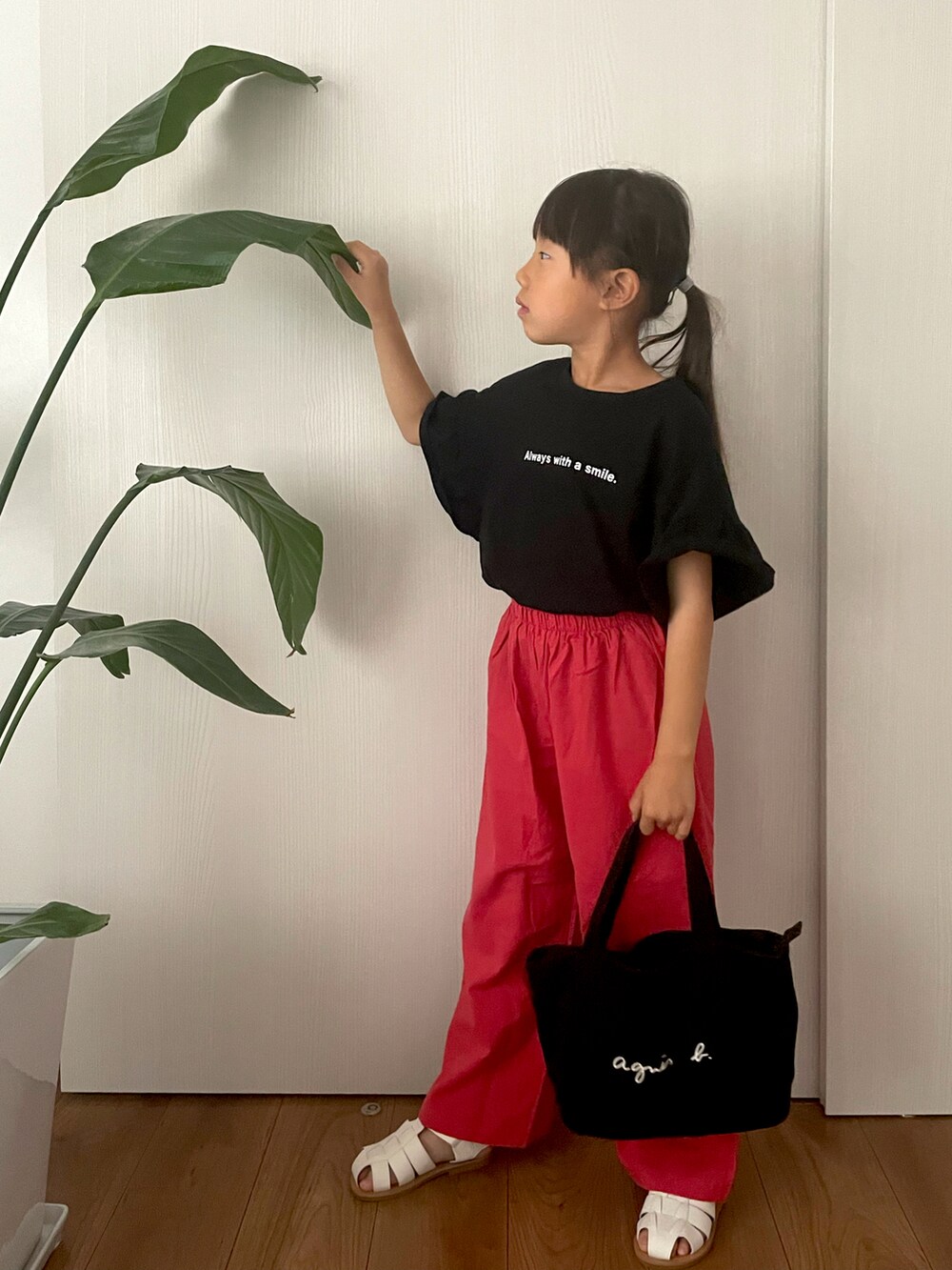 ブラック系のTシャツ/カットソー、ブラック系のハンドバッグ、ホワイト系のサンダルを着用したキッズの春コーディネートの2枚目の写真