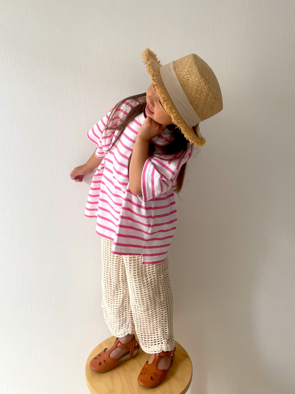 ピンク系のTシャツ/カットソー、ベージュ系のパンツ、ブラウン系のサンダルを着用したキッズの春コーディネートの2枚目の写真