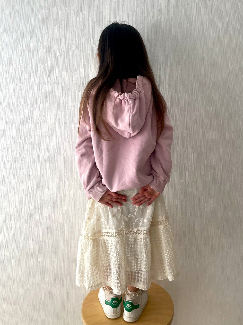 ピンク系のパーカー、ベージュ系のスカート、ホワイト系のスニーカーを着用したキッズの春コーディネートの3枚目の写真