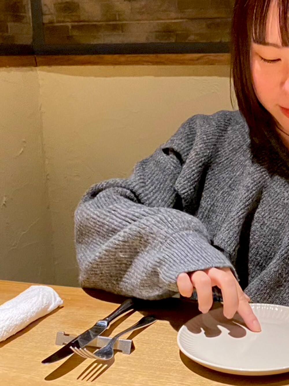 グレー系のニット/セーター、シルバー系のネックレスを着用したレディースの冬コーディネートの2枚目の写真