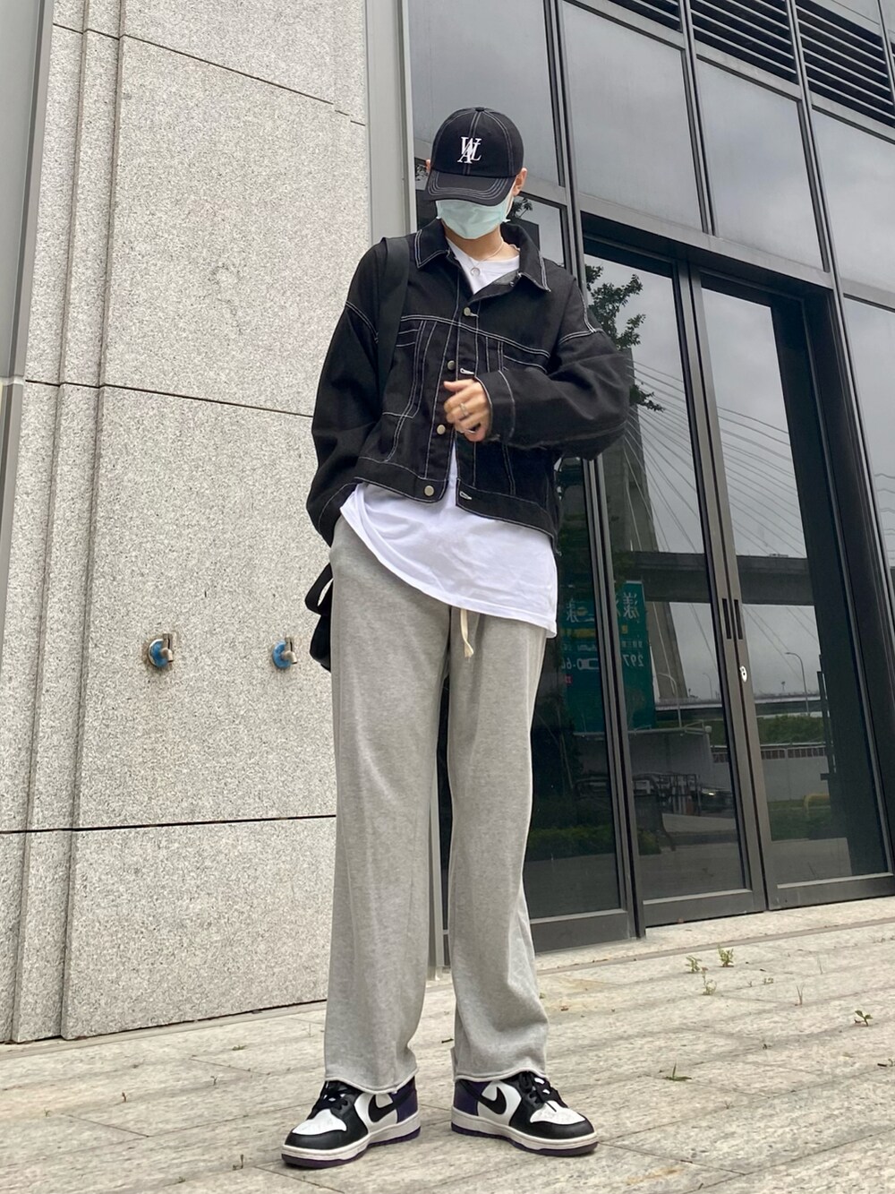 ホワイト系のスニーカー、ブラック系のデニムジャケット、ブラック系のキャップを着用したメンズの春コーディネートの2枚目の写真