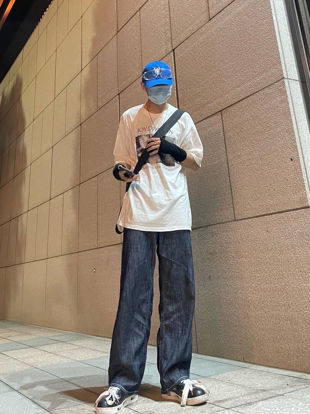 ホワイト系のTシャツ/カットソー、ブラック系のスニーカー、ブルー系のキャップを着用したメンズの春コーディネートの2枚目の写真