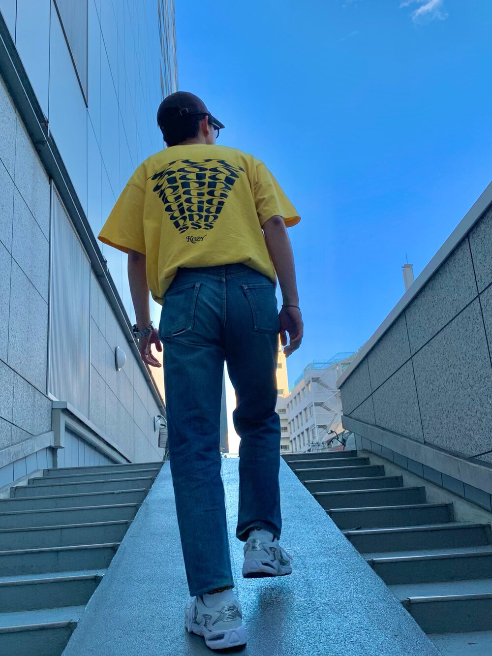 イエロー系のTシャツ/カットソー、ブルー系のデニムパンツ、ホワイト系のスニーカーを着用したメンズの夏コーディネートの2枚目の写真