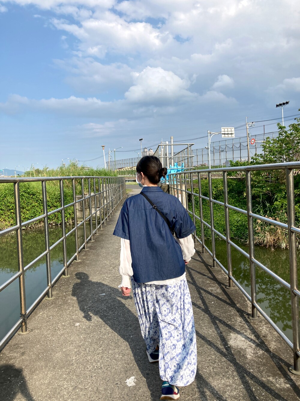 ブルー系のチノパンツ、その他のスニーカー、ブラウン系のショルダーバッグを着用したレディースの春コーディネートの2枚目の写真