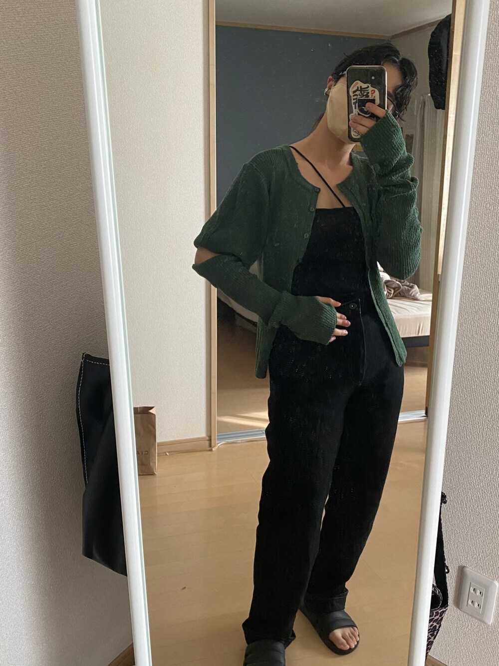 グリーン系のニット/セーター、ブラック系のデニムパンツを着用したレディースの春コーディネートの2枚目の写真