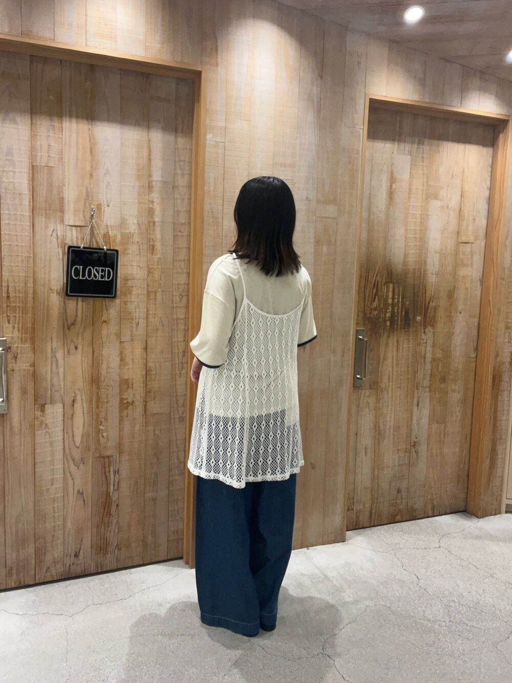 ブラック系のチュニック、ブルー系のデニムパンツ、ホワイト系のTシャツ/カットソーを着用したレディースの夏コーディネートの3枚目の写真