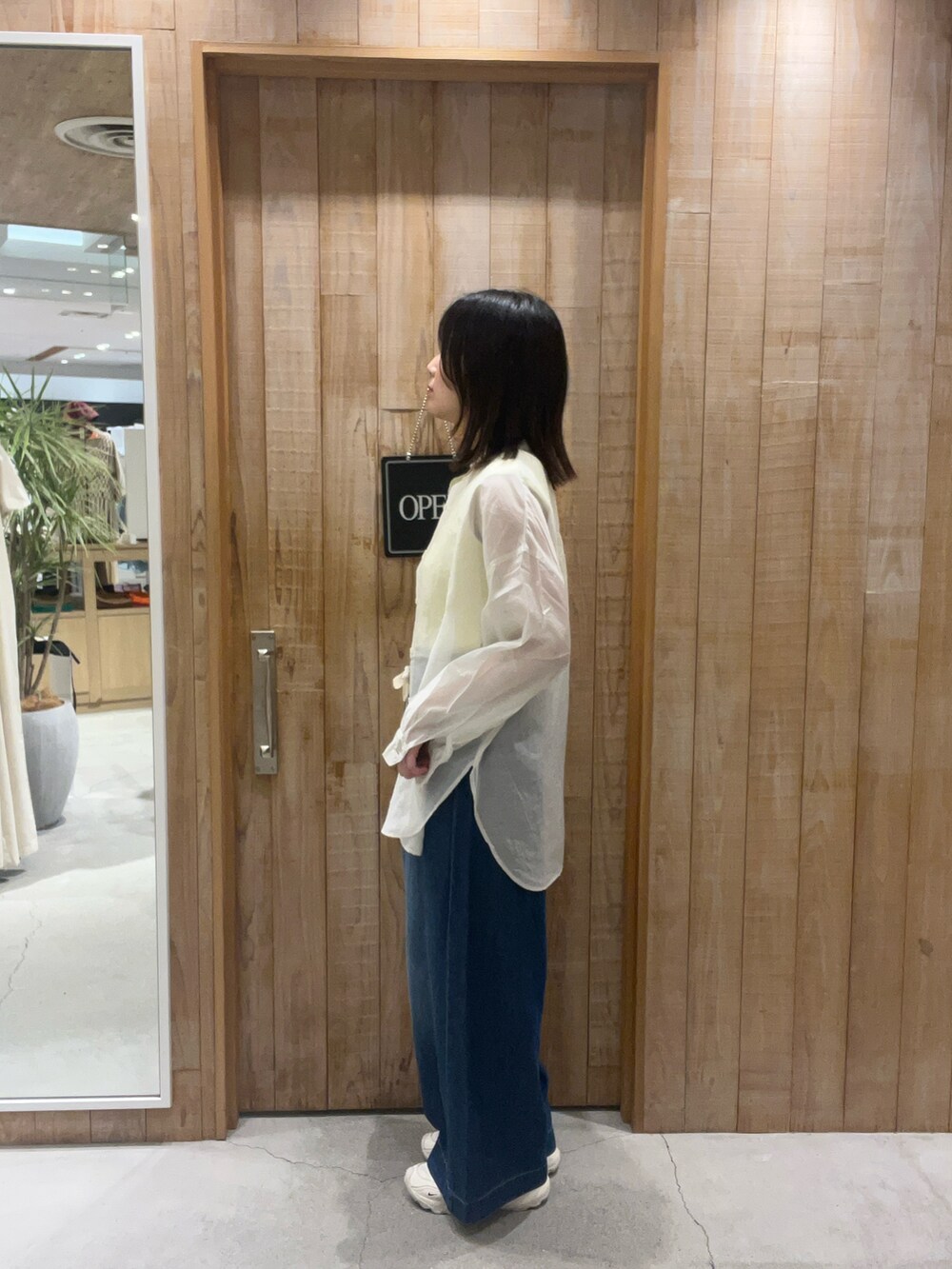イエロー系のタンクトップ、グレー系のシャツ/ブラウス、ブルー系のデニムパンツを着用したレディースの夏コーディネートの2枚目の写真