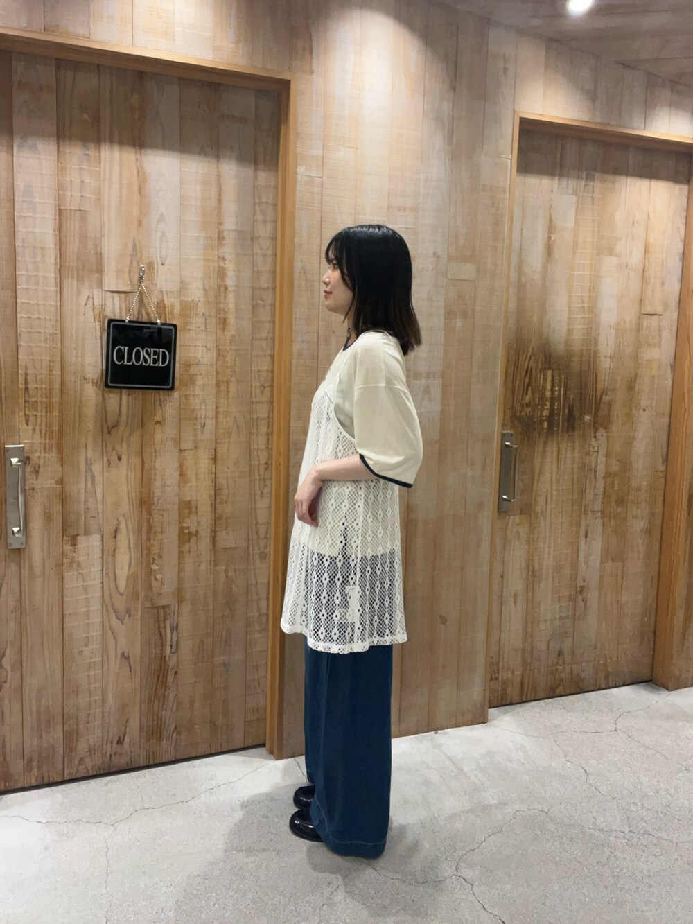 ブラック系のチュニック、ブルー系のデニムパンツ、ホワイト系のTシャツ/カットソーを着用したレディースの夏コーディネートの2枚目の写真