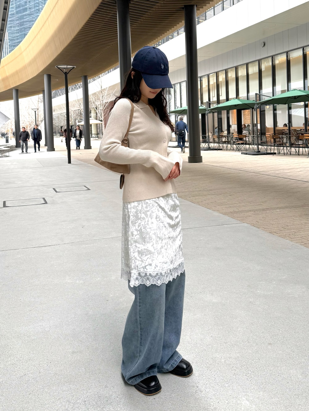 ホワイト系のニット/セーター、ブルー系のデニムパンツ、ベージュ系のショルダーバッグを着用したレディースの冬コーディネートの2枚目の写真