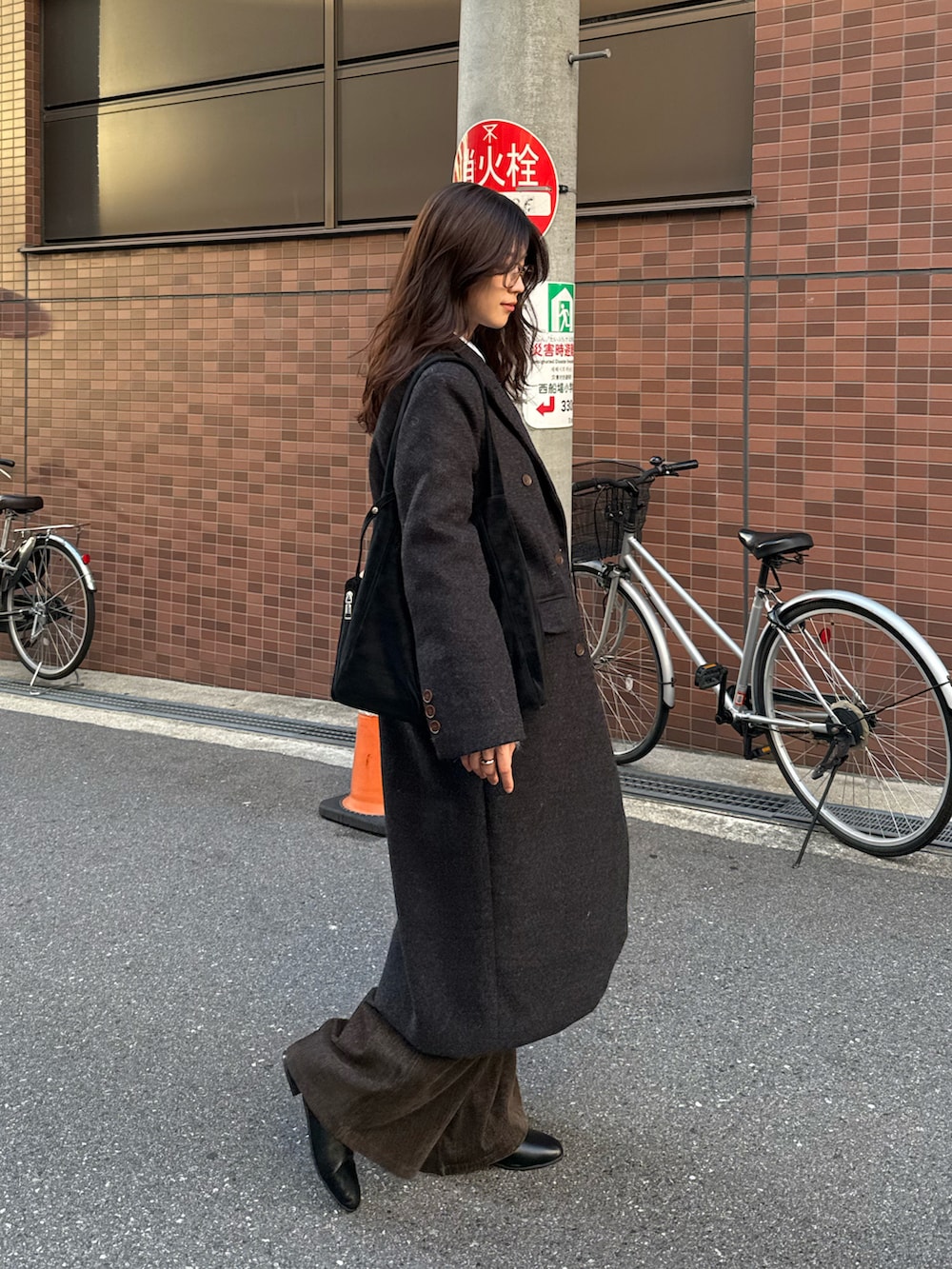 ブラック系のチェスターコート、ブラック系のトートバッグ、グレー系のニット/セーターを着用したレディースの秋コーディネートの3枚目の写真