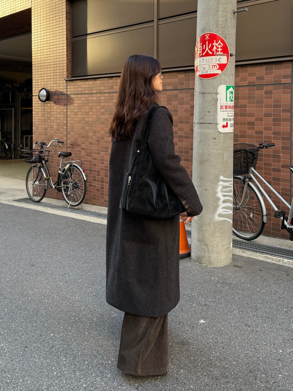 ブラック系のチェスターコート、ブラック系のトートバッグ、グレー系のニット/セーターを着用したレディースの秋コーディネートの4枚目の写真