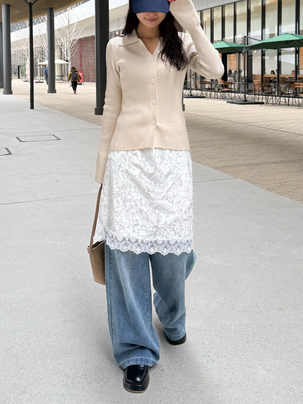 ホワイト系のニット/セーター、ブルー系のデニムパンツ、ベージュ系のショルダーバッグを着用したレディースの冬コーディネートの4枚目の写真