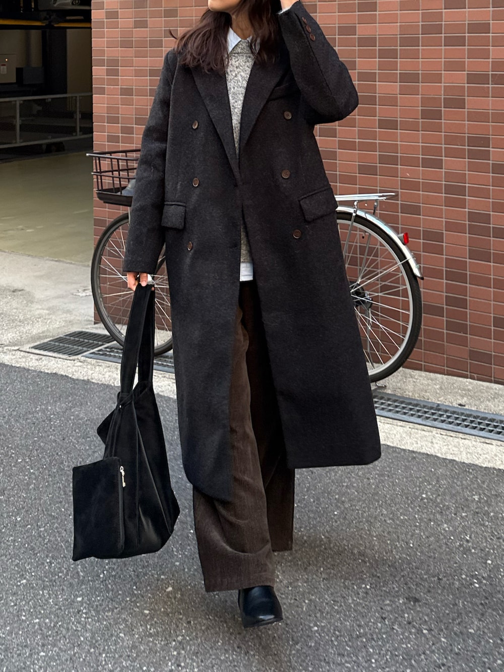 ブラック系のチェスターコート、ブラック系のトートバッグ、グレー系のニット/セーターを着用したレディースの秋コーディネートの5枚目の写真