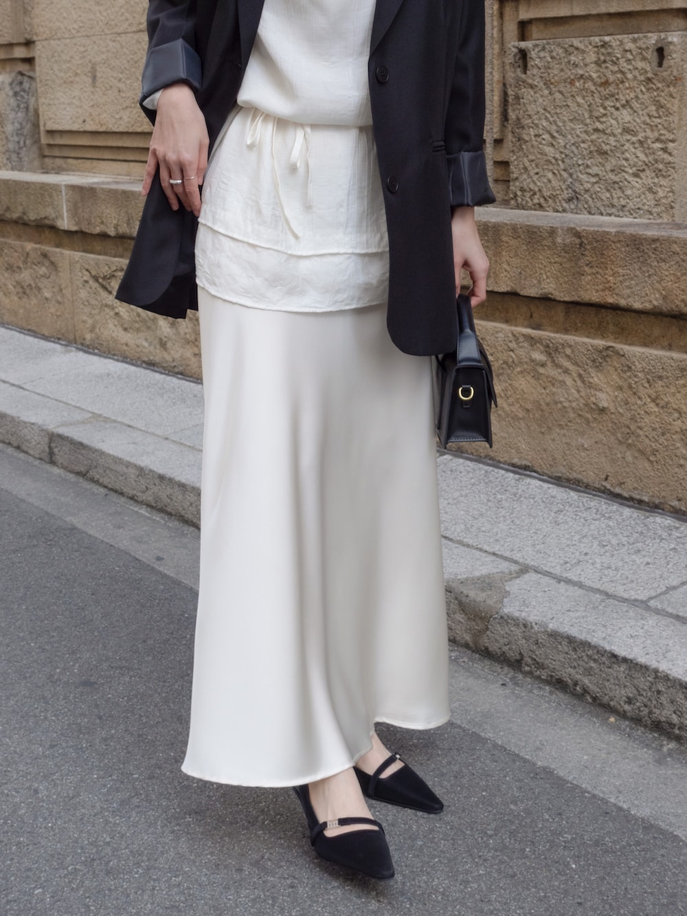 ブラック系のテーラードジャケット、ホワイト系のスカート、ブラック系のパンプスを着用したレディースの冬コーディネートの3枚目の写真