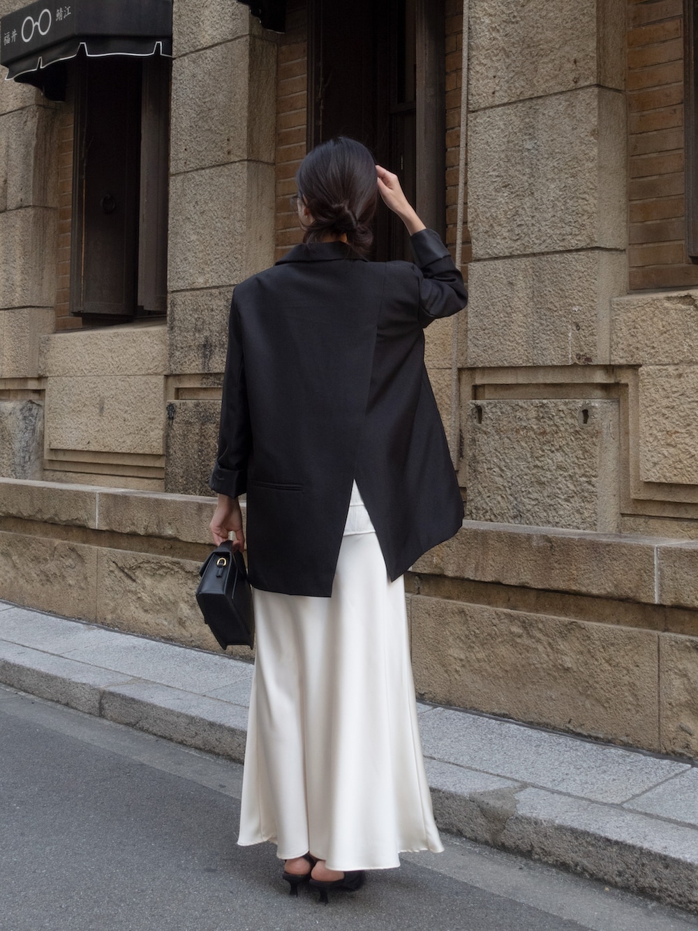 ブラック系のテーラードジャケット、ホワイト系のスカート、ブラック系のパンプスを着用したレディースの冬コーディネートの5枚目の写真