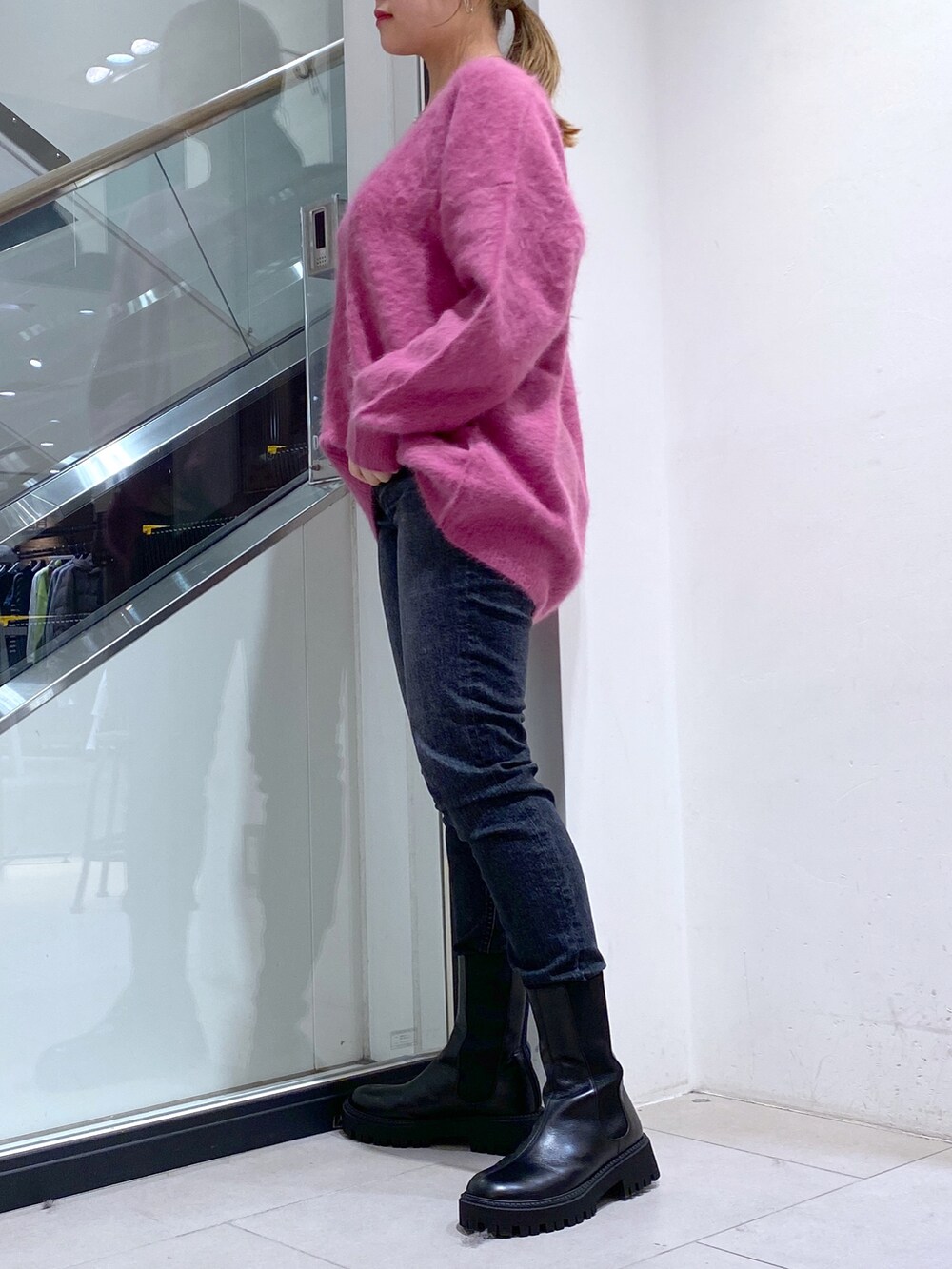 ブラック系のデニムパンツ、グリーン系のニット/セーター、ブラック系のブーツを着用したレディースの秋コーディネートの2枚目の写真