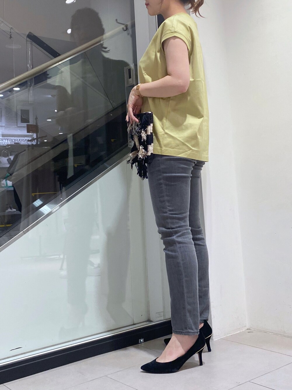 グレー系のデニムパンツ、ブラック系のクラッチバッグ、ホワイト系のTシャツ/カットソーを着用したレディースの夏コーディネートの2枚目の写真