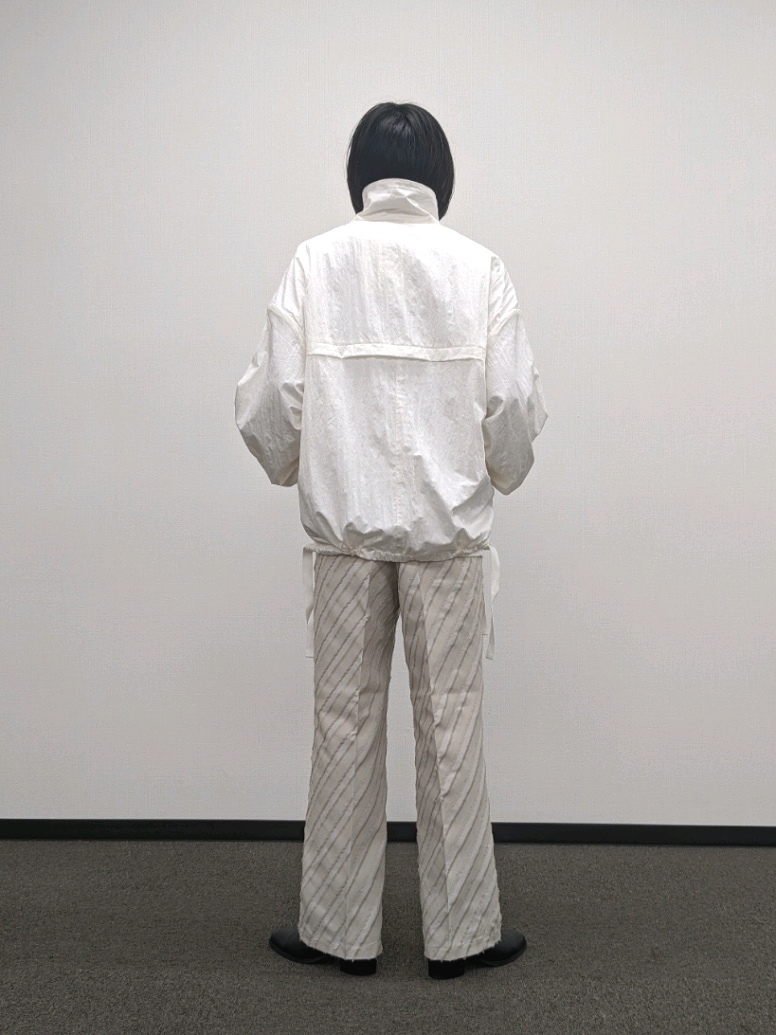 ホワイト系のブルゾン、ベージュ系のその他パンツ、ブラック系のブーツを着用したメンズの秋コーディネートの3枚目の写真