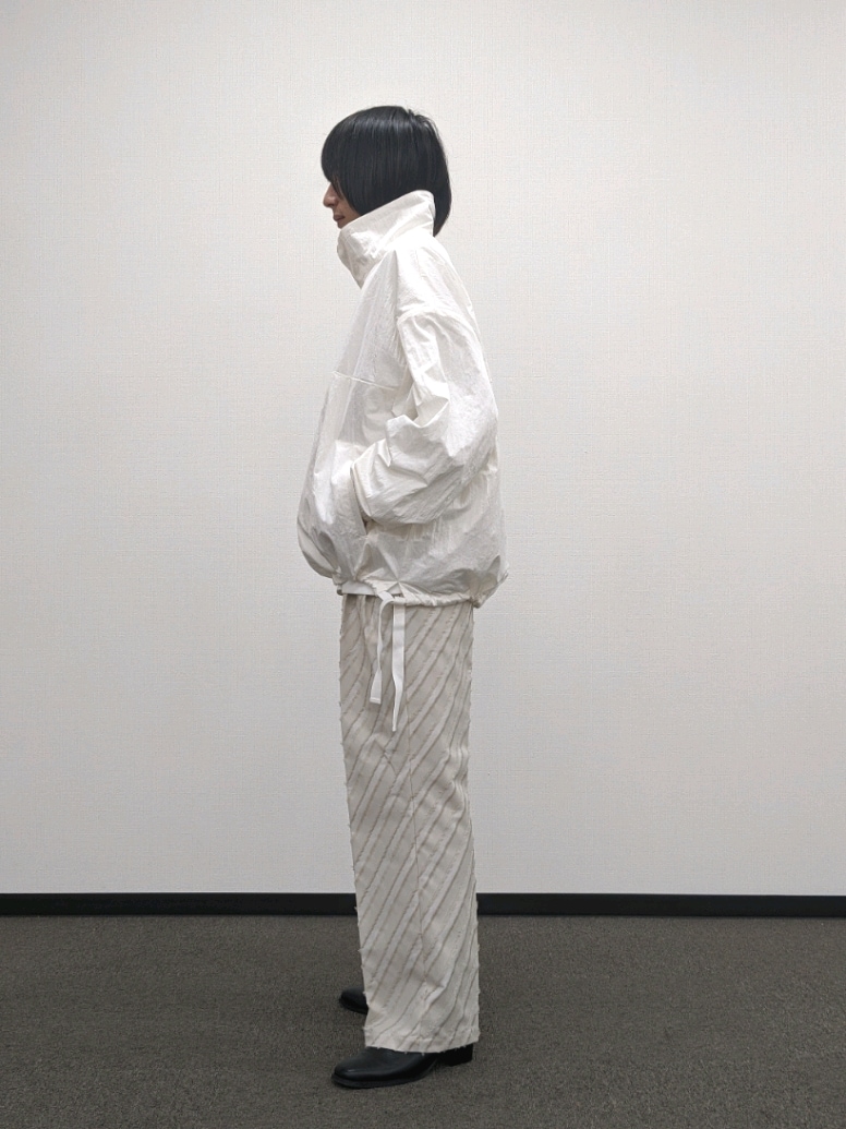 ホワイト系のブルゾン、ベージュ系のその他パンツ、ブラック系のブーツを着用したメンズの秋コーディネートの2枚目の写真