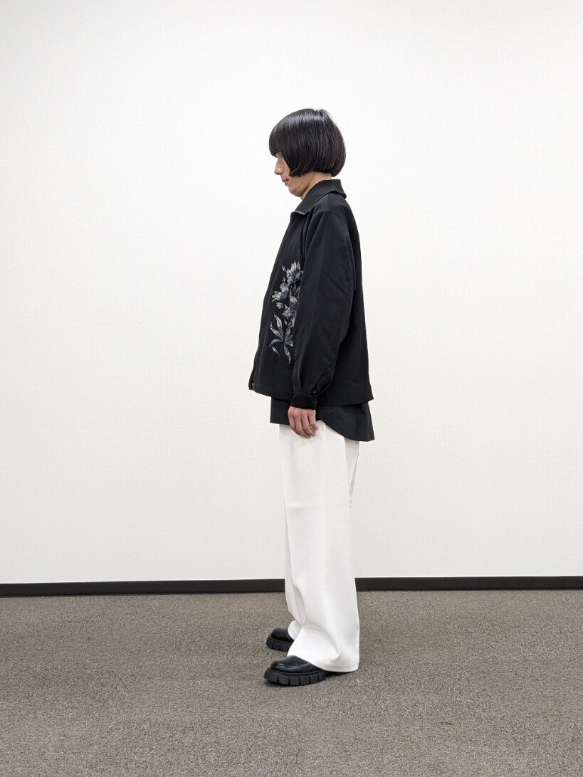 ブラック系のブルゾン、ホワイト系のスラックス、ブラック系のブーツを着用したメンズの秋コーディネートの2枚目の写真