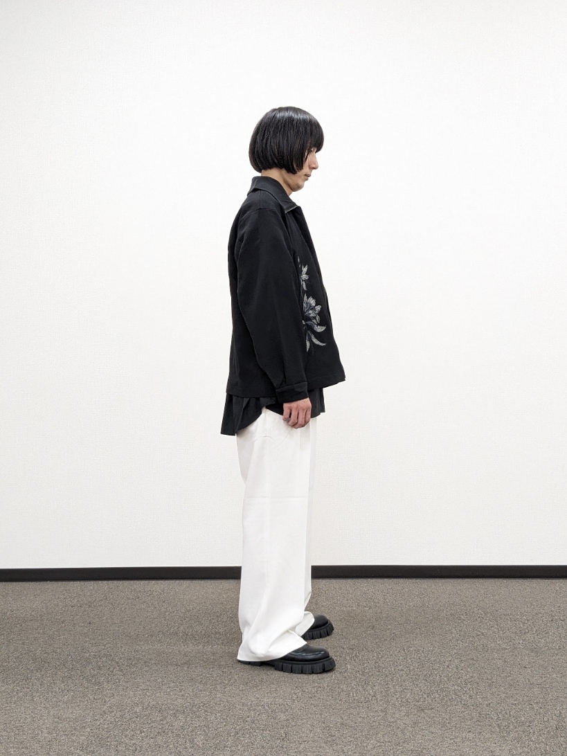 ブラック系のブルゾン、ホワイト系のスラックス、ブラック系のブーツを着用したメンズの秋コーディネートの4枚目の写真