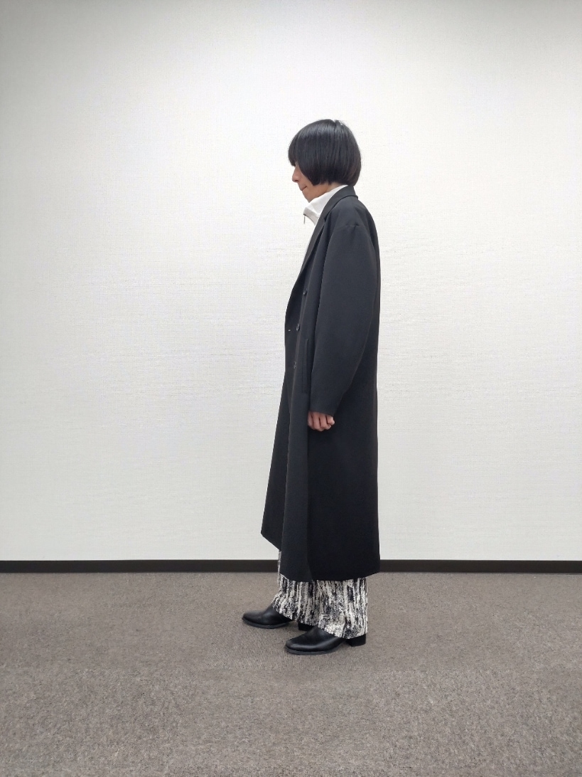 ブラック系のチェスターコート、ホワイト系のTシャツ/カットソー、グレー系のその他パンツを着用したメンズの秋コーディネートの2枚目の写真